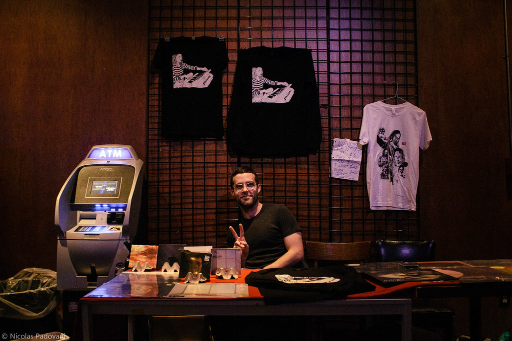 Cool guy sitting at merch desk, next to ATM.